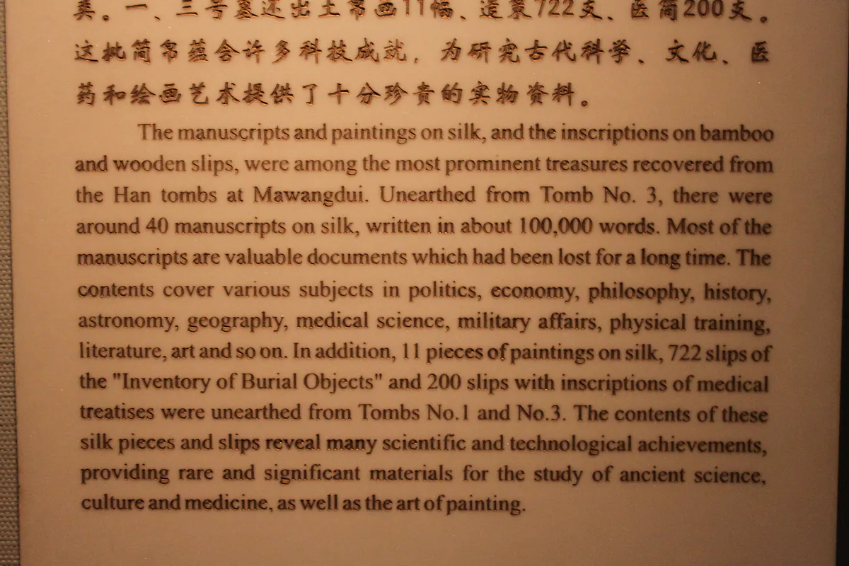 Ancient Chinese manuscripts written on silk, wooden tablets and bound bamboo slips, displayed in a case.