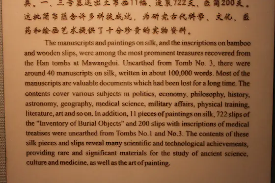 Ancient Chinese manuscripts written on silk, wooden tablets and bound bamboo slips, displayed in a case.