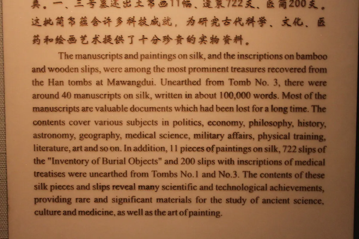 Ancient Chinese manuscripts written on silk, wooden tablets and bound bamboo slips, displayed in a case.