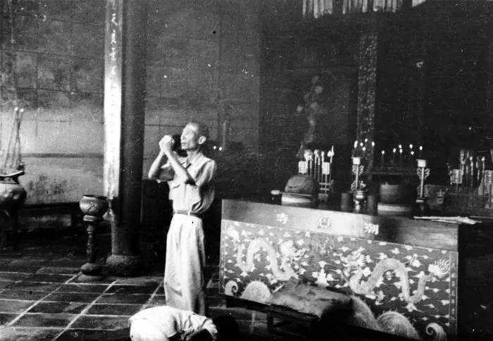 Historic photograph of Chinese worshippers praying with incense inside a temple in Cheribon, West Java.