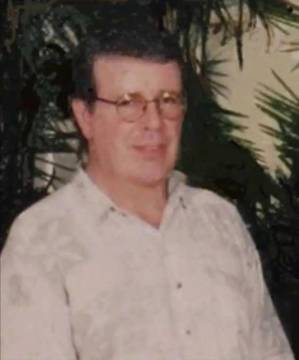 Jim McMillan, an older man in glasses and a pale patterned shirt, photographed in front of foliage.
