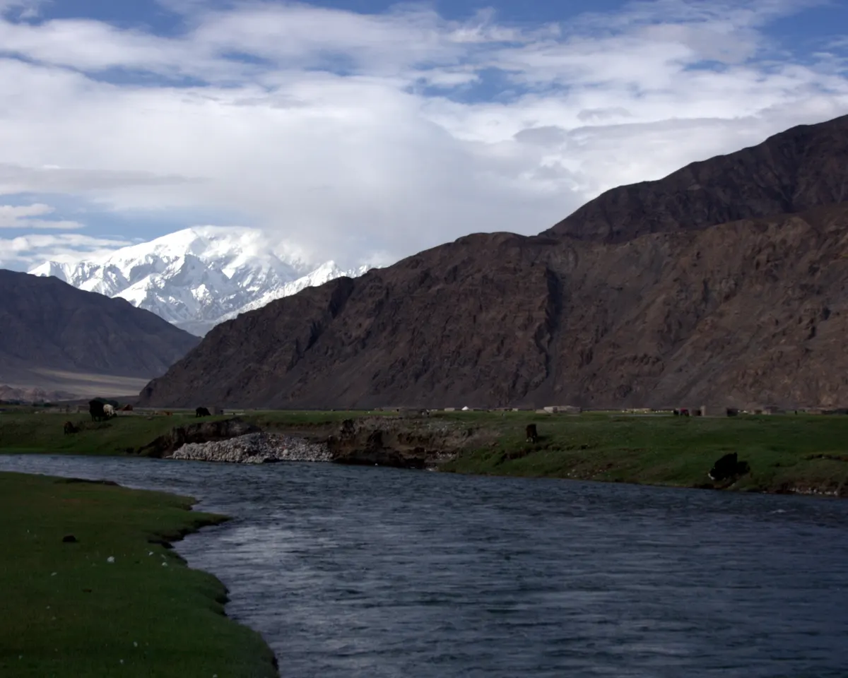 Photograph of the Kunlun mountains: a bare, sunlit range of rock and snow under a wide sky.