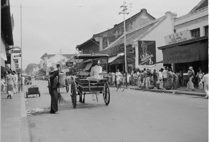 Historic photograph of a street in Java lined with Chinese shopfronts, including a batik shop.